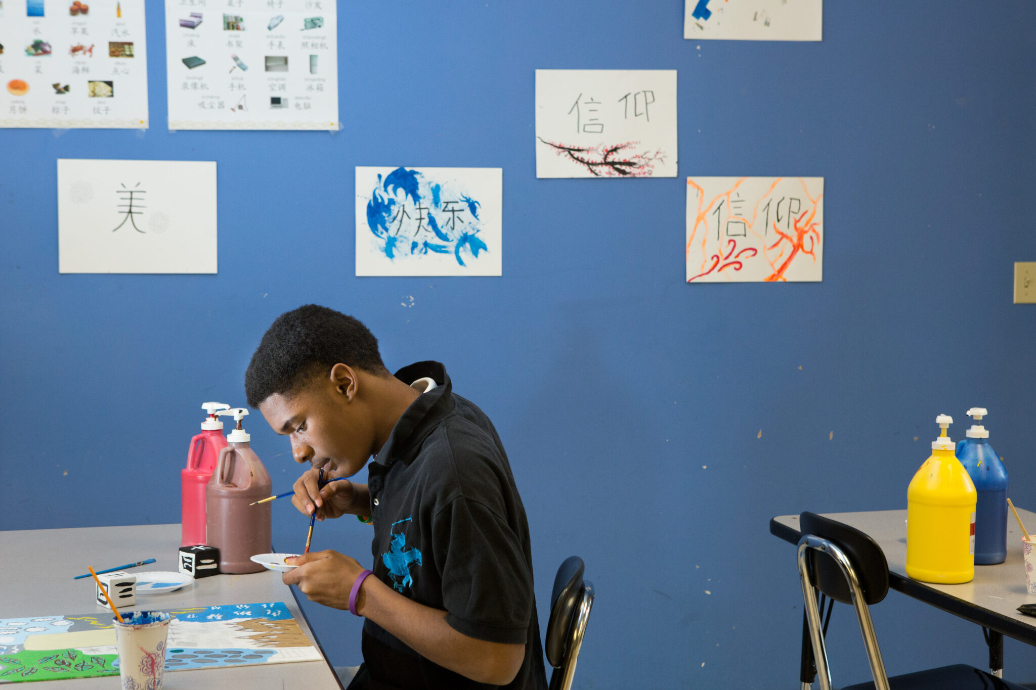 A person in an art classroom looks down at his artwork.
