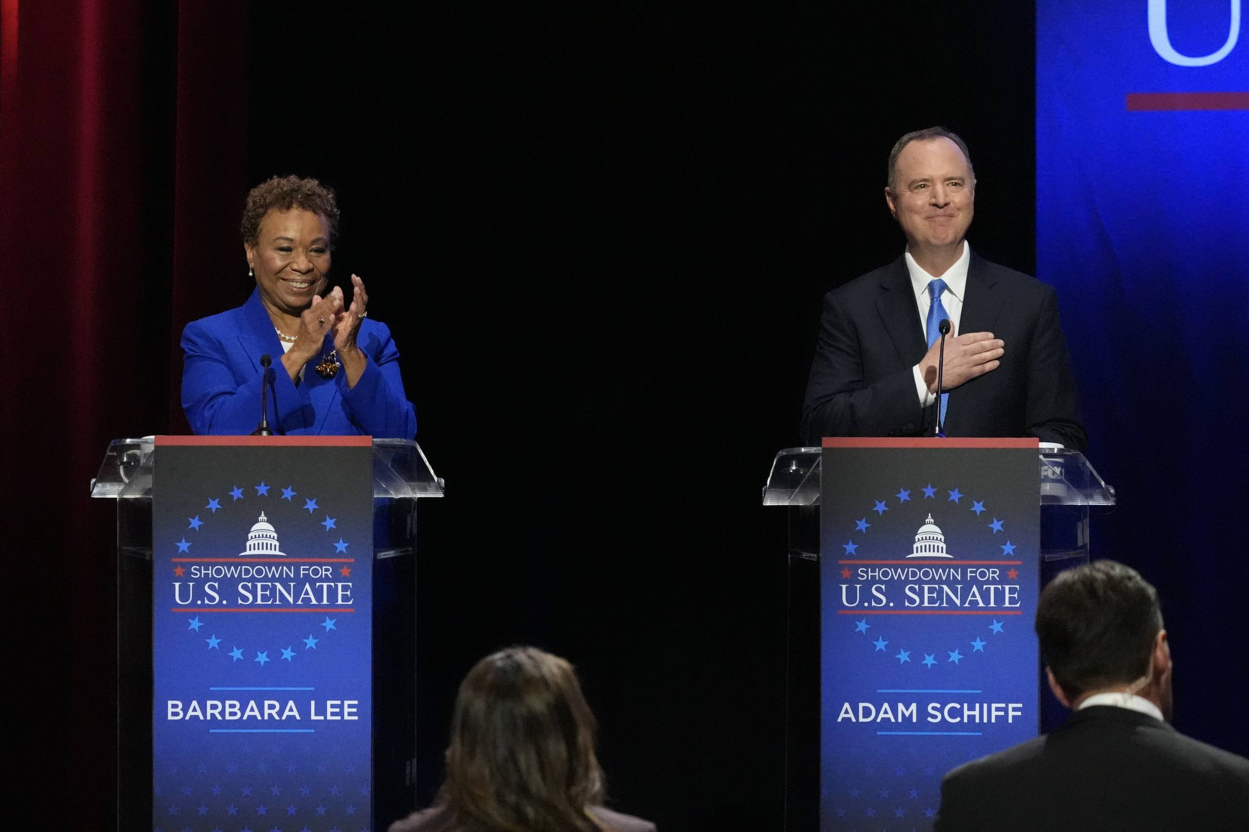 Woman and man stand in front of lecterns ready to debate.