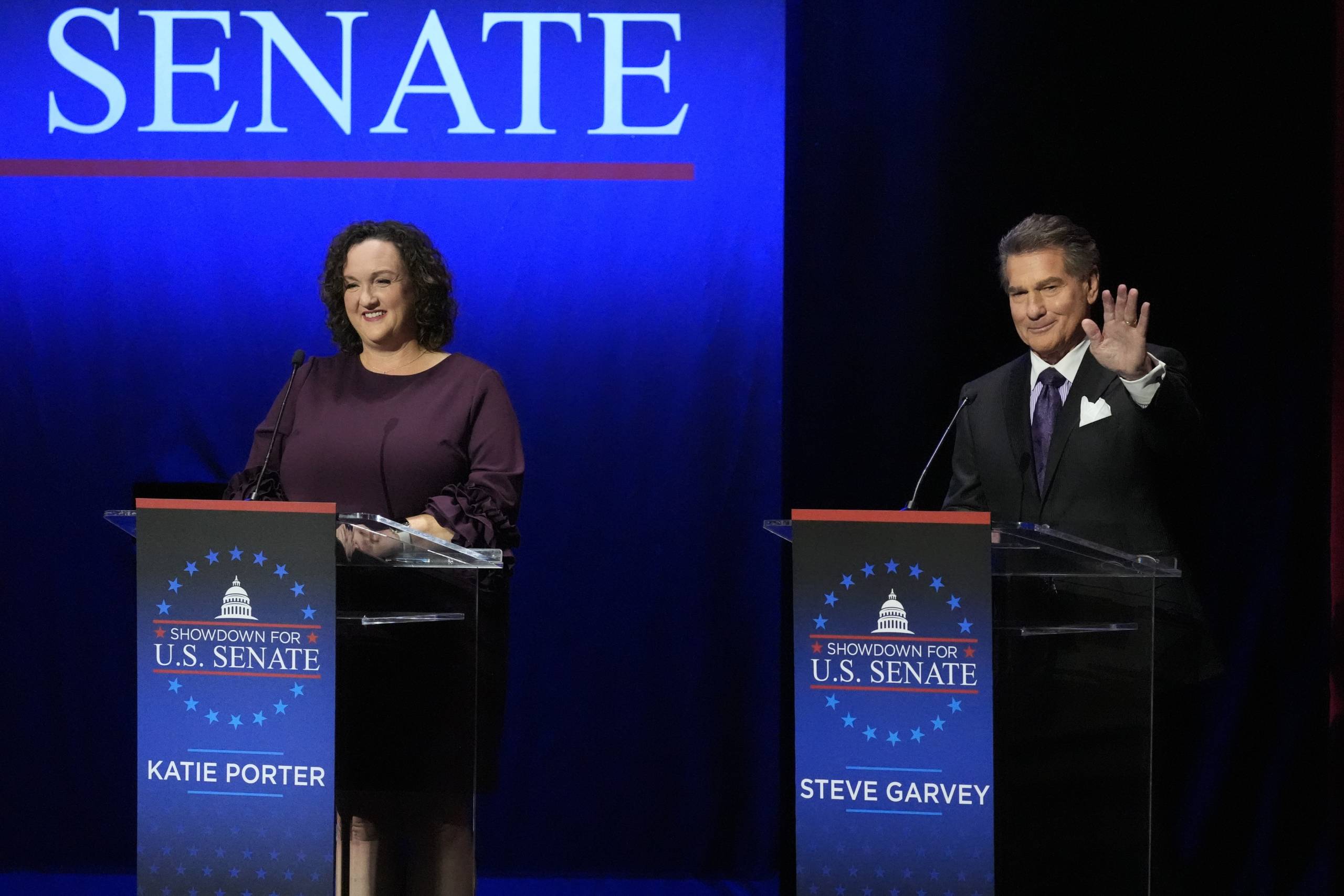 Woman and man stand in front of lectern before a debate