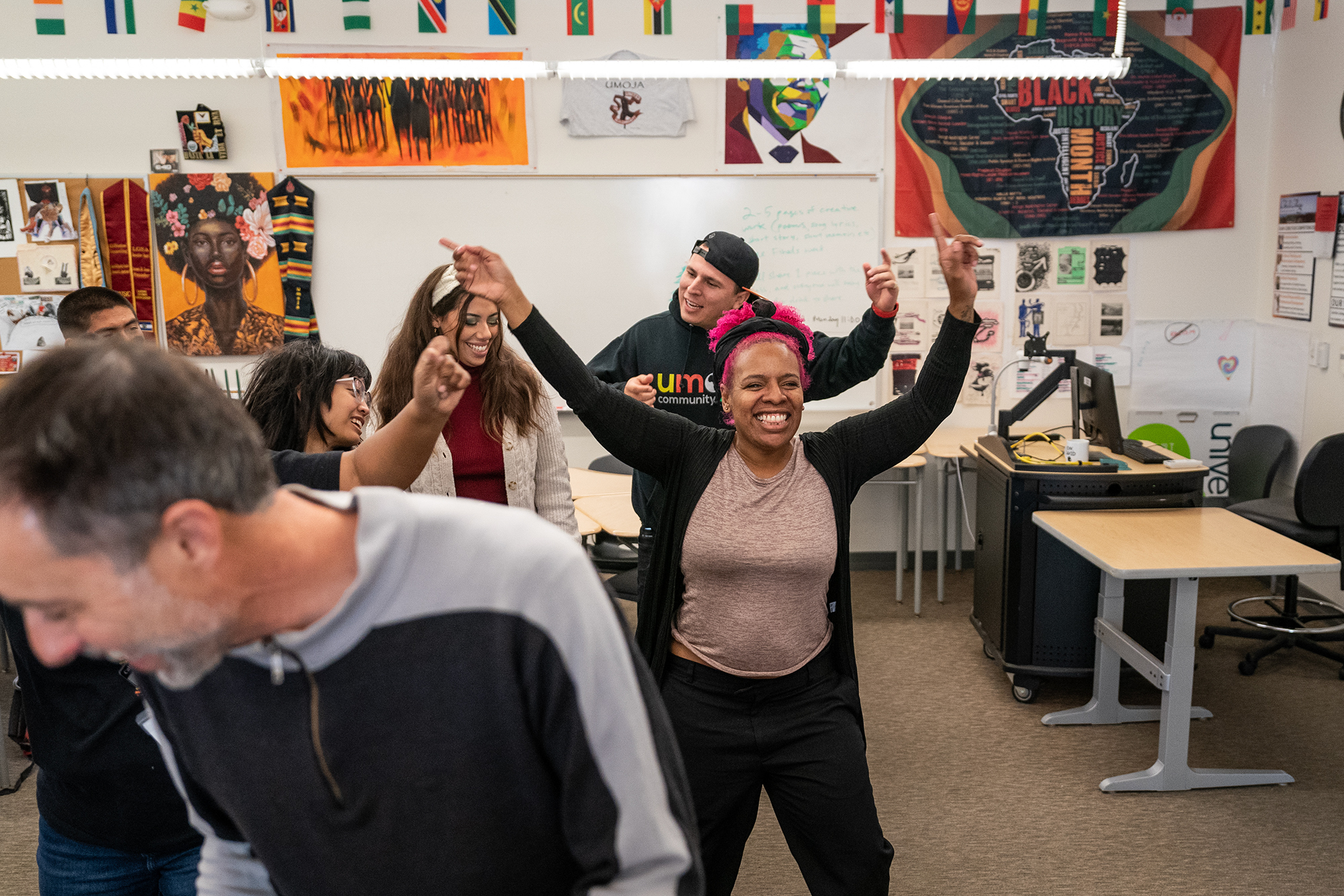 A teacher happily dancing in a classroom of community college students.