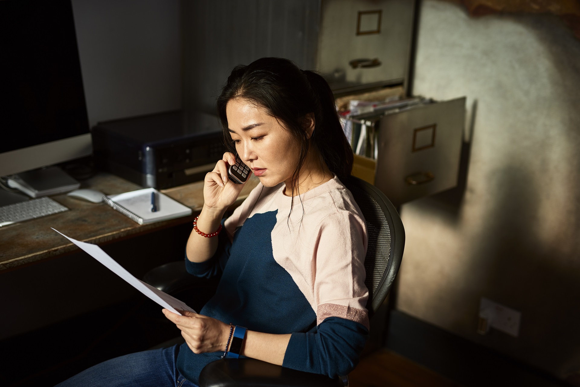 A woman on the phone while looking over her bills.