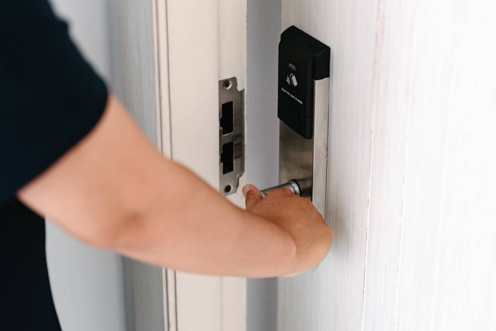 A hand opens a white door.