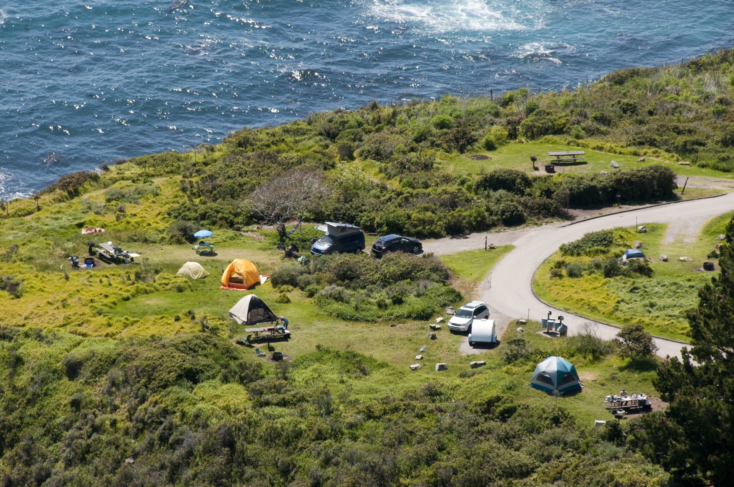 Tents by the sea seen from a distance above.