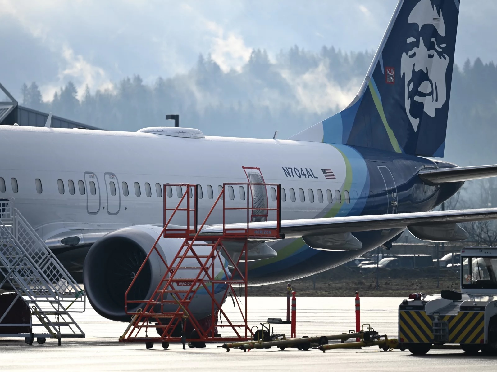A plane on a tarmac with scaffolding around it as crews work on maintenance, repairs.