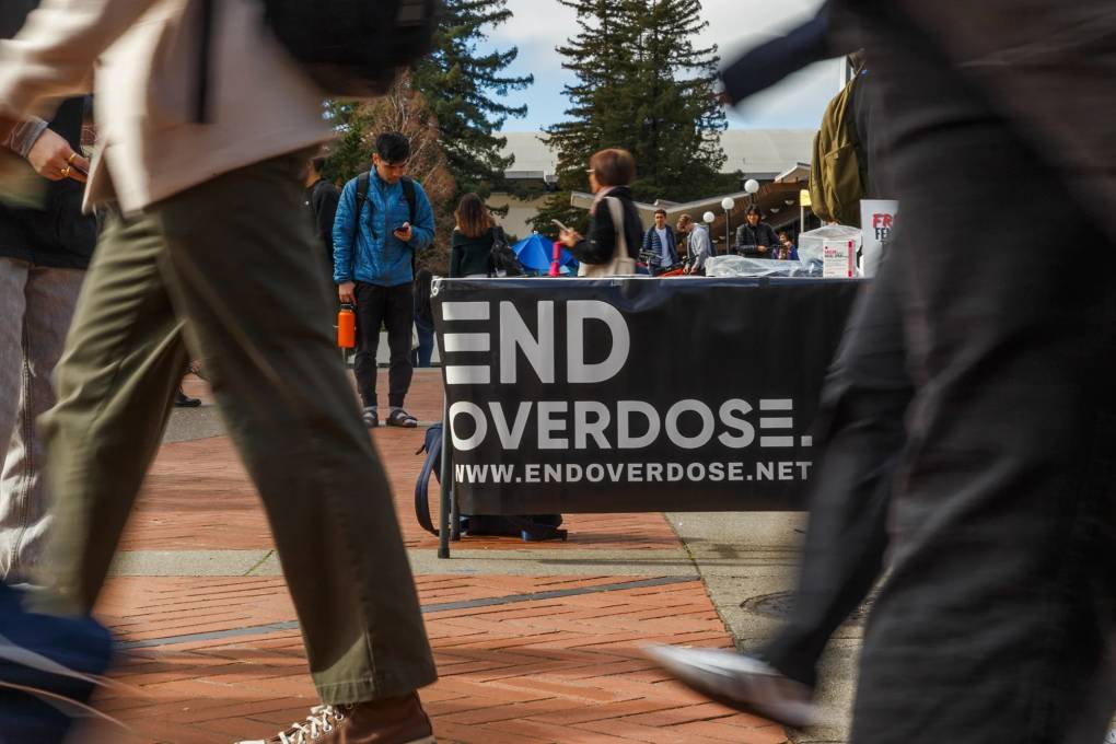Students are seen walking in a plaza with a banner in the middle that reads "End Overdose."