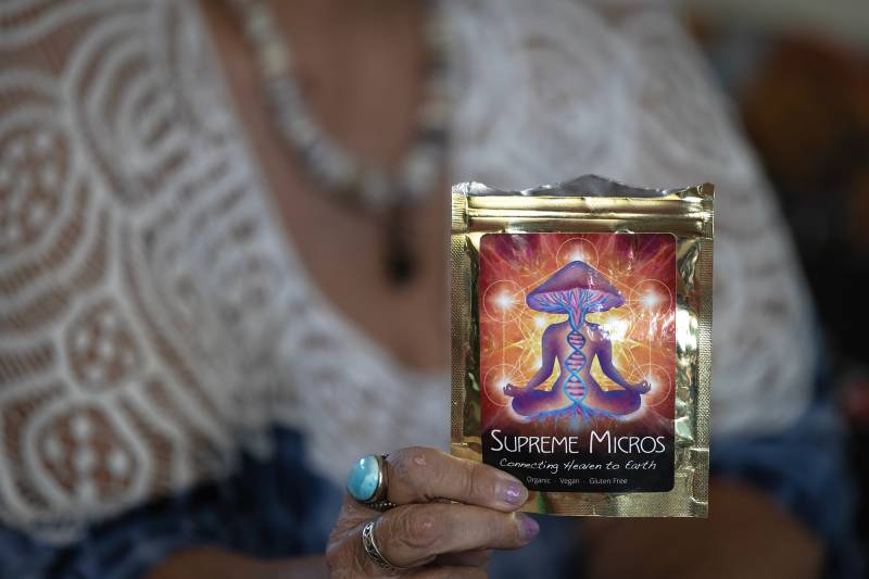 A person holds a bag with an illustration of a figure with a mushroom head in a meditative pose.