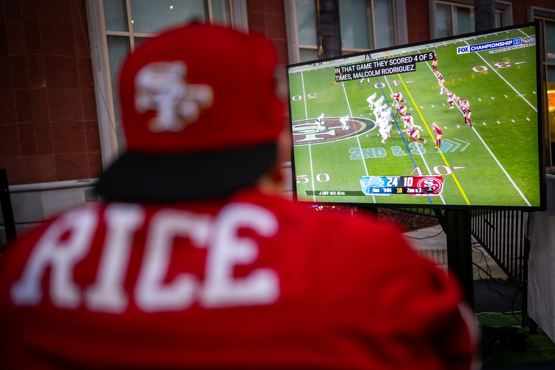 A person with a red jersey watched football on TV.