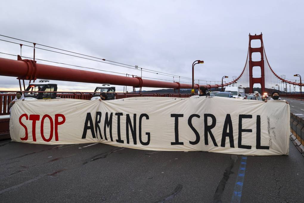 People hold up a banner that reads "Stop Arming Israel" across the Golden Gate Bridge, blocking traffic.