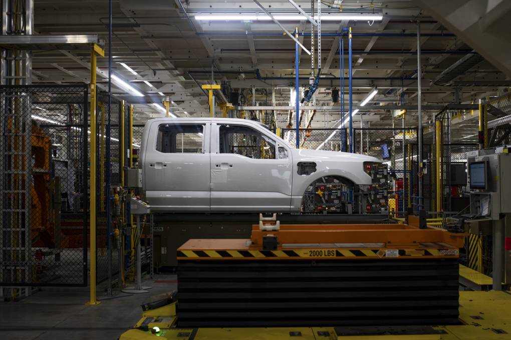 An electric, heavy-duty pickup truck is seen being fabricated in a warehouse.