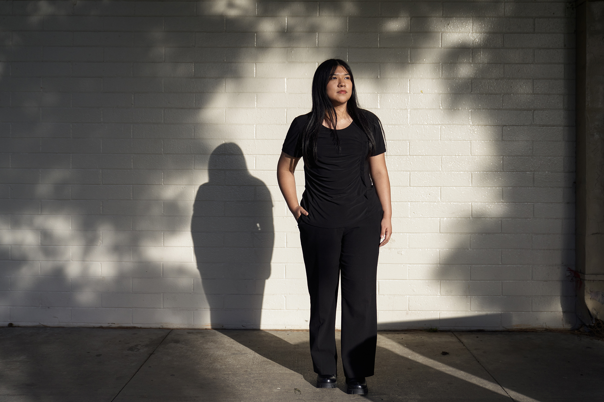 A woman stands by a wall.