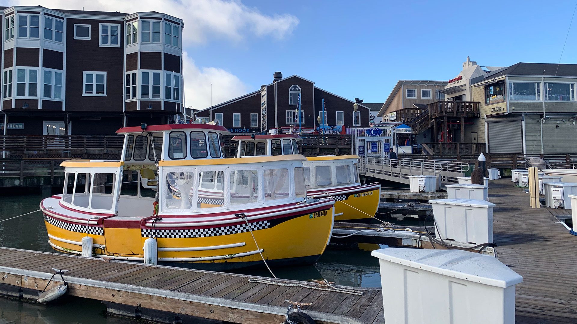 Several yellow boats are tied up at a pier with buildings in the background.