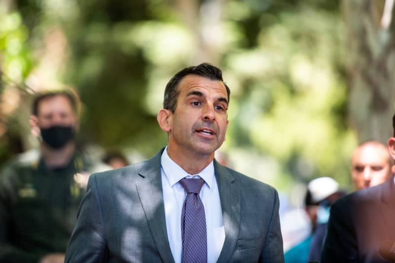 A man in a gray suit and a purple tie.