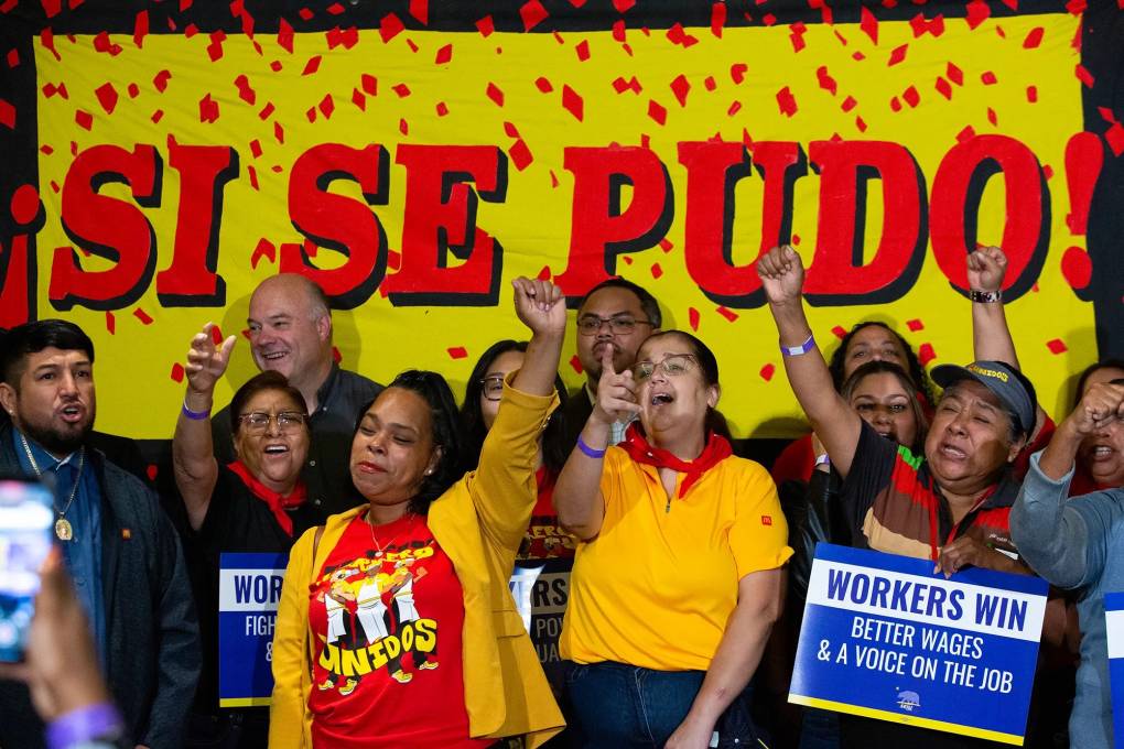 Workers stand in front of a sign that reads, "Si se pudo."