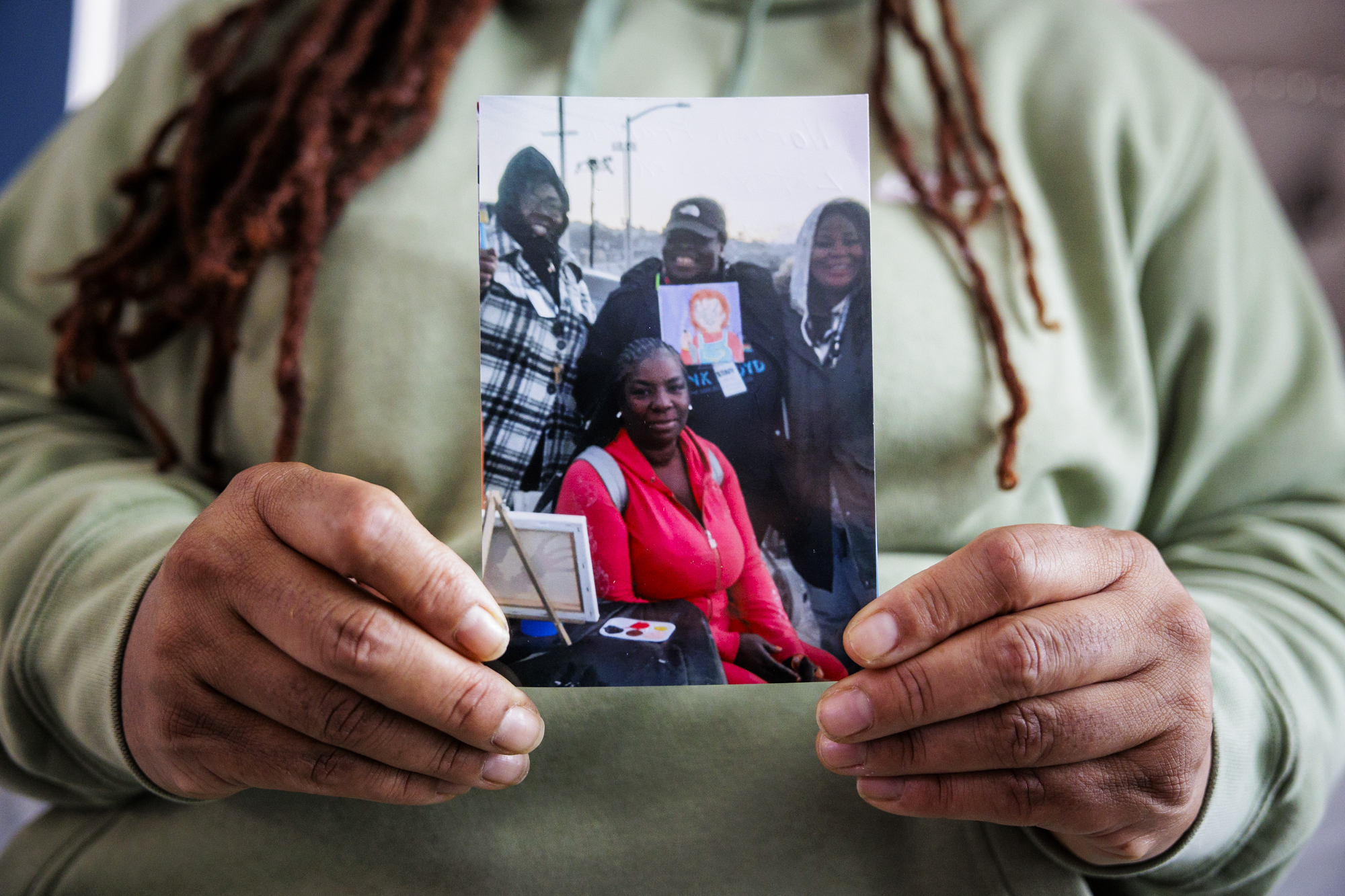 An African American woman is seen from the neck down holding a photo with four African Americans.