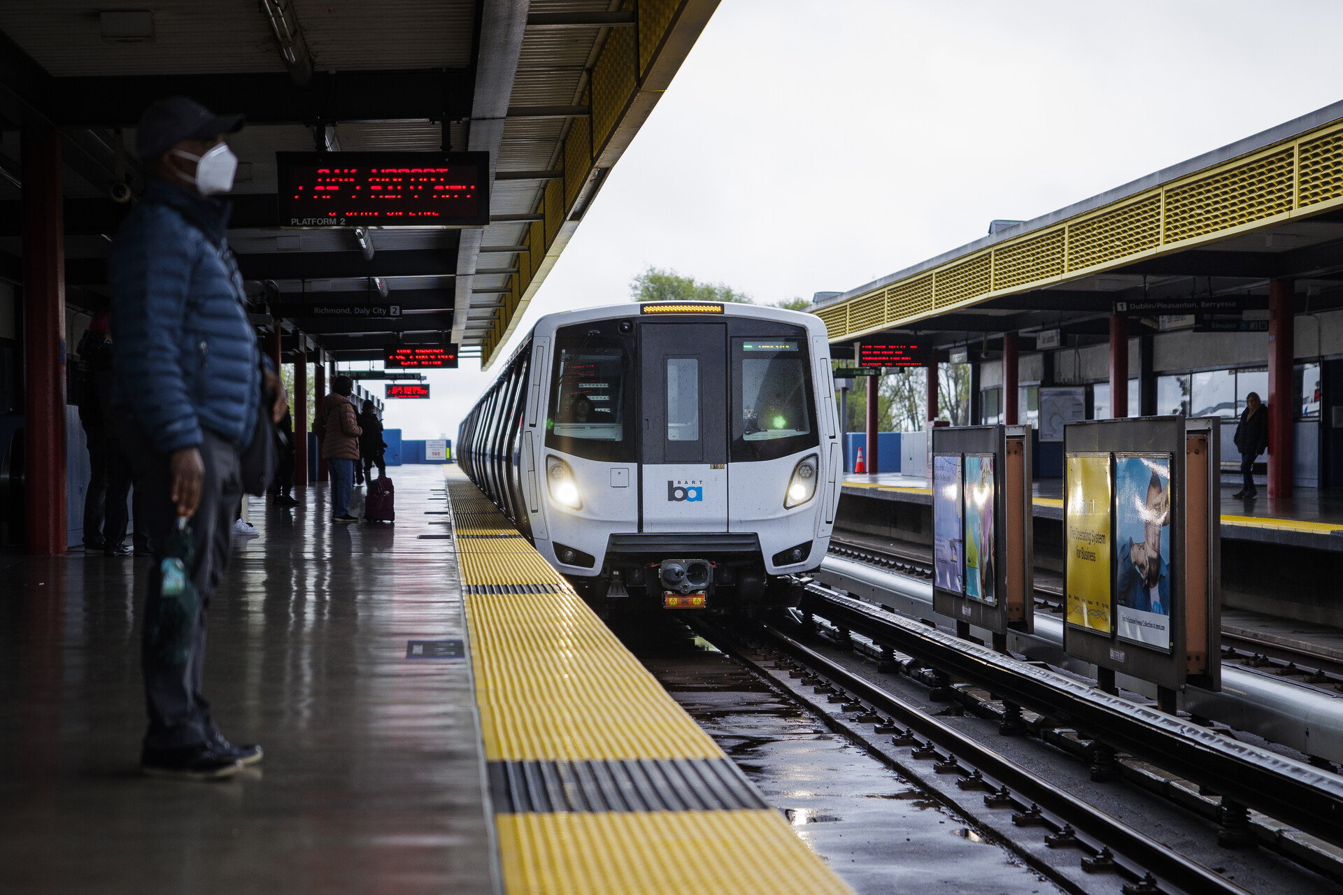 A train approaches the station with people waiting.