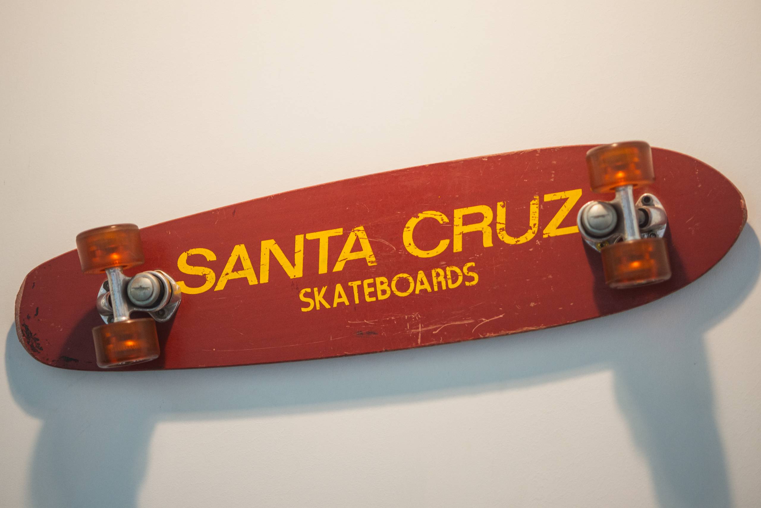 The bottom of a skateboard hanging on a wall reads "Santa Cruz Skateboards."