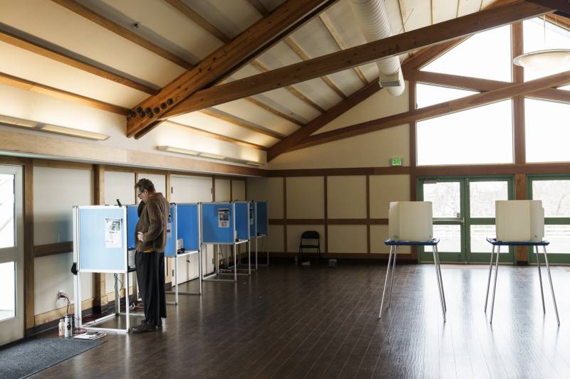 A man votes in what looks like an attic.