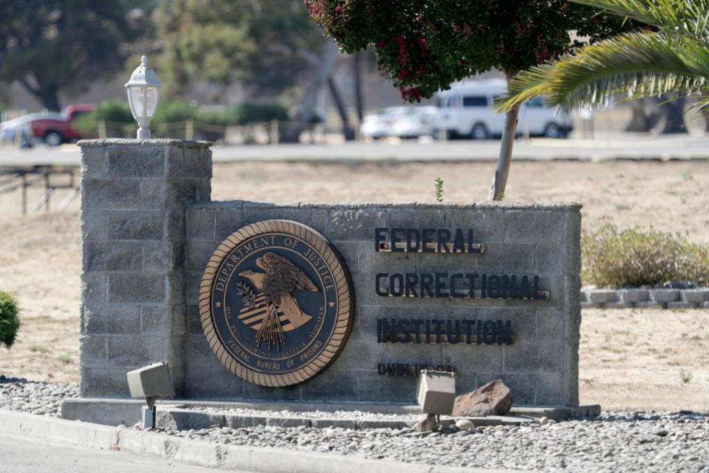 A stone sign outside with an emblem and the words "Federal Correctional Institution" written on it.