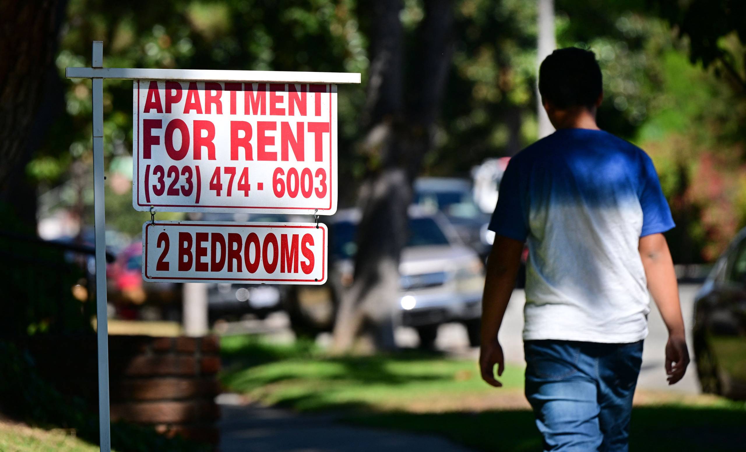 A man walks by a 'for rent' sign.