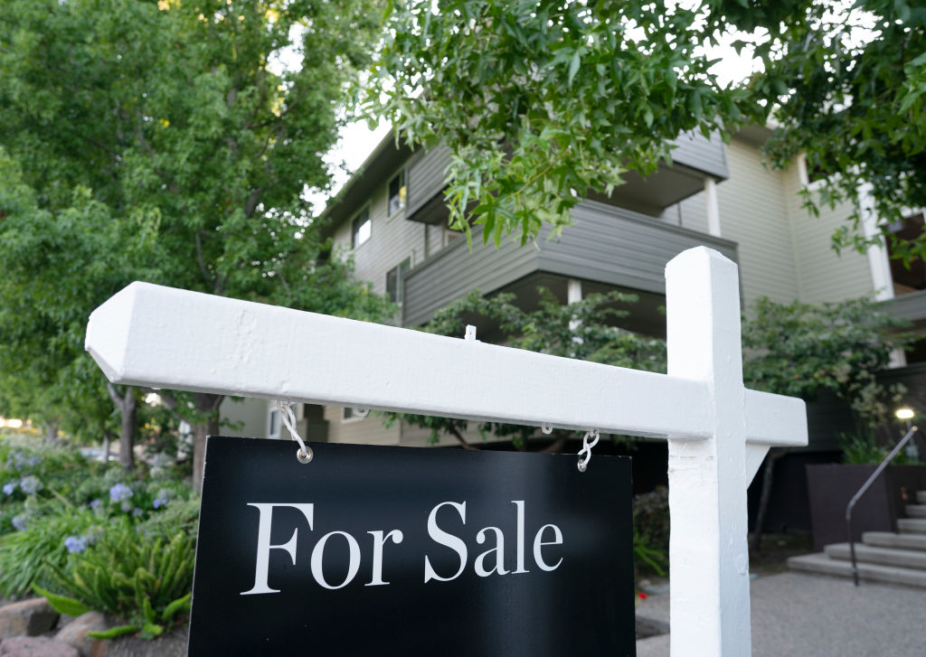 A black sign on a white post with the words "For Sale" written on it.