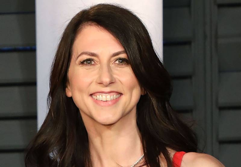 A white woman with long brown hair smiles at the camera.
