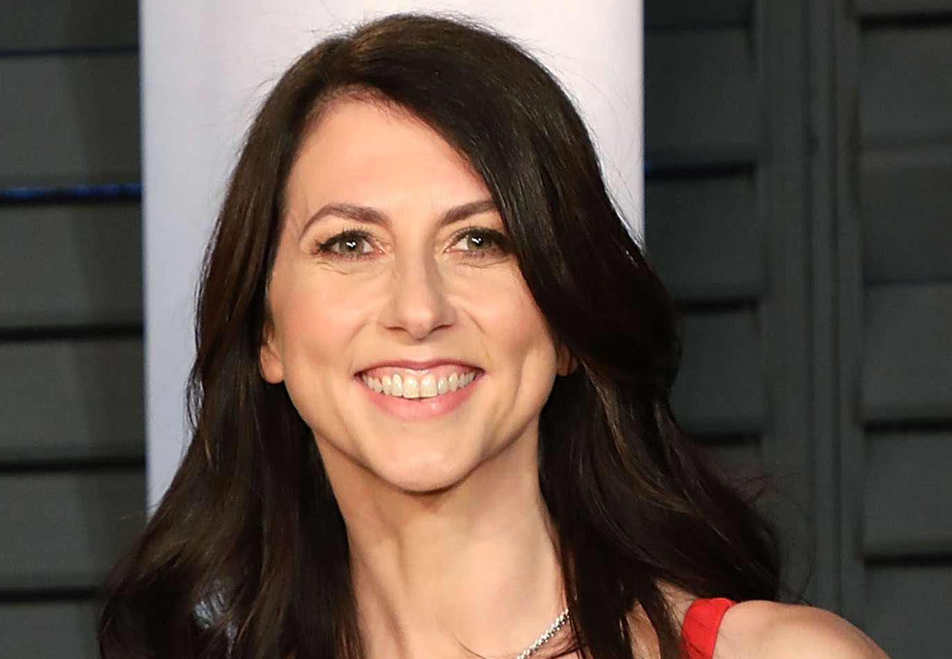 A white woman with long brown hair smiles at the camera.