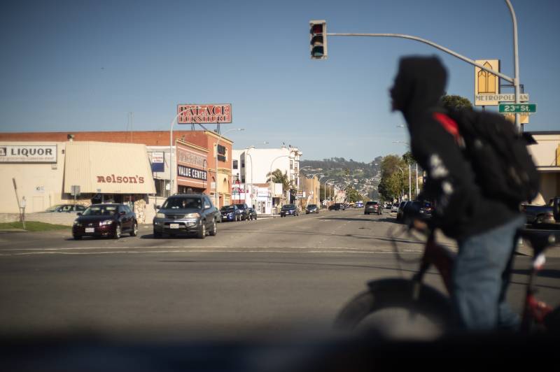 A person rides a bike through an intersection with cars waiting at a stoplight.