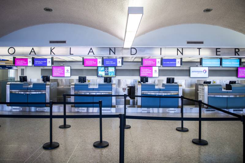 An airport terminal with line dividers and luggage check with a sign that reads 
