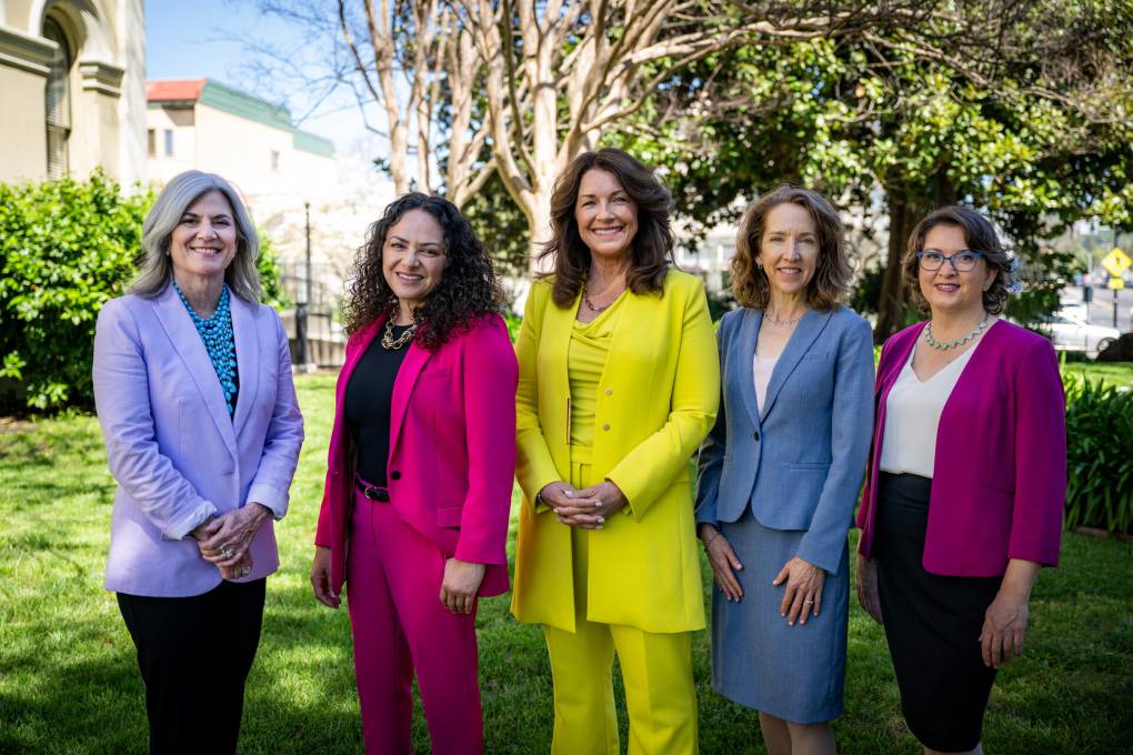 Five women stand side by side, smiling at the camera.