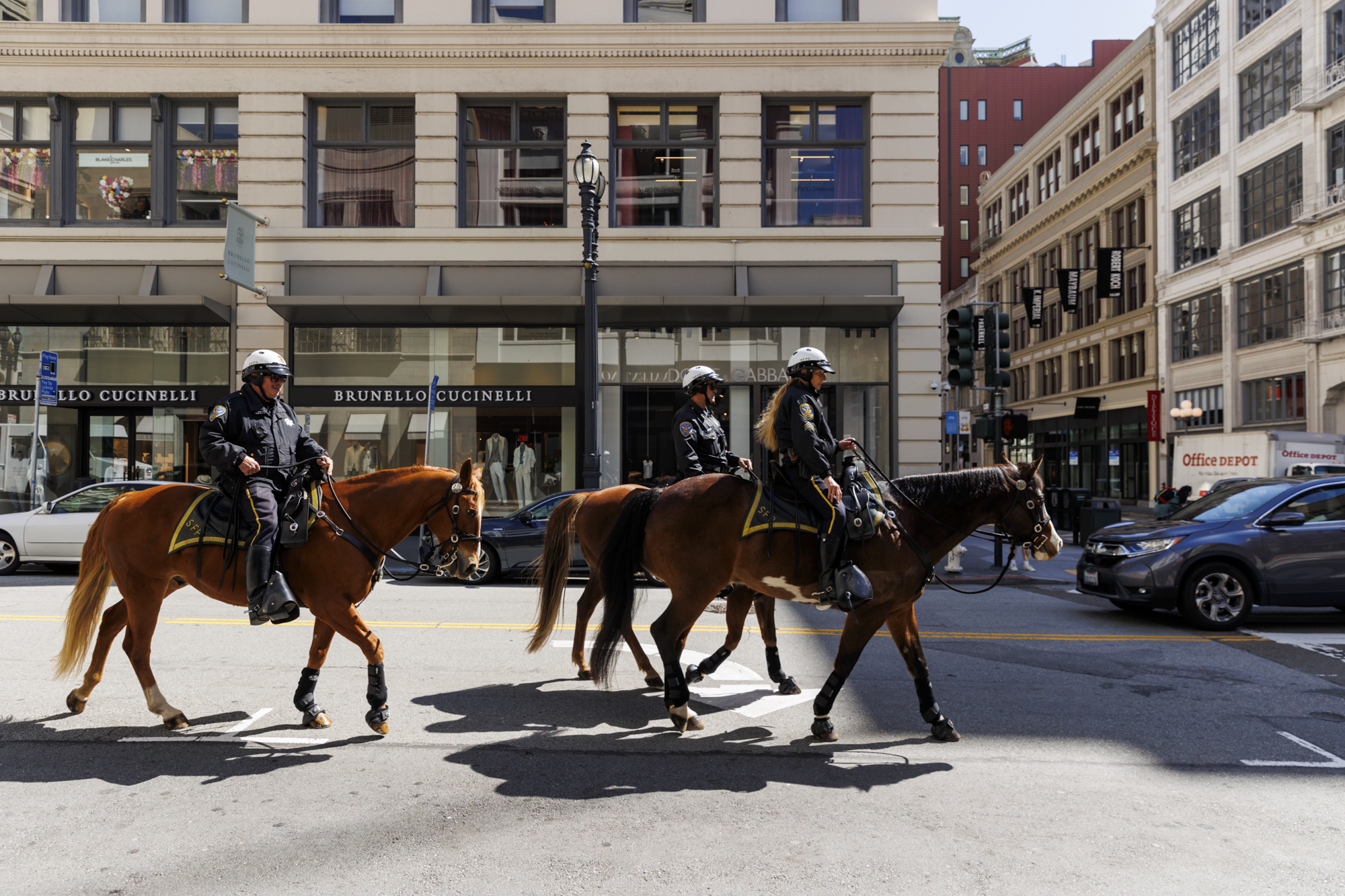 Three police officers on horseback ride down a city street near Union Square.