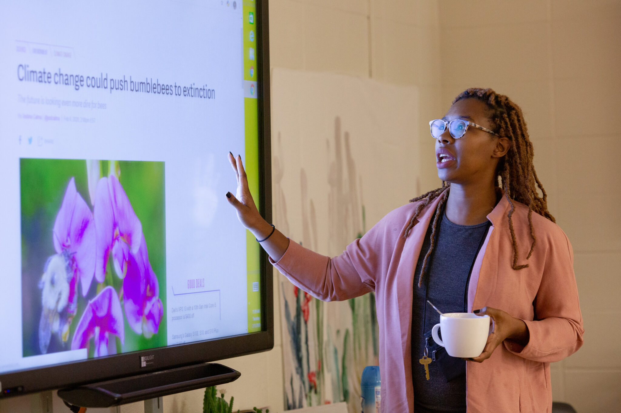 a Black woman stands in front of a screen and presents