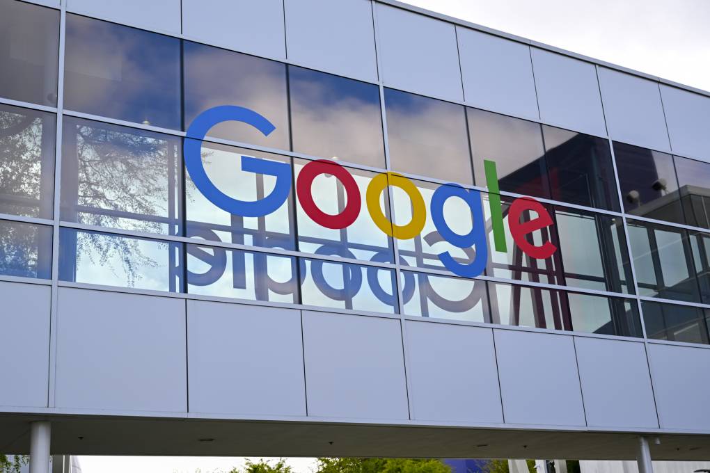 A building with glass windows and a huge multicolored logo reads, "Google."
