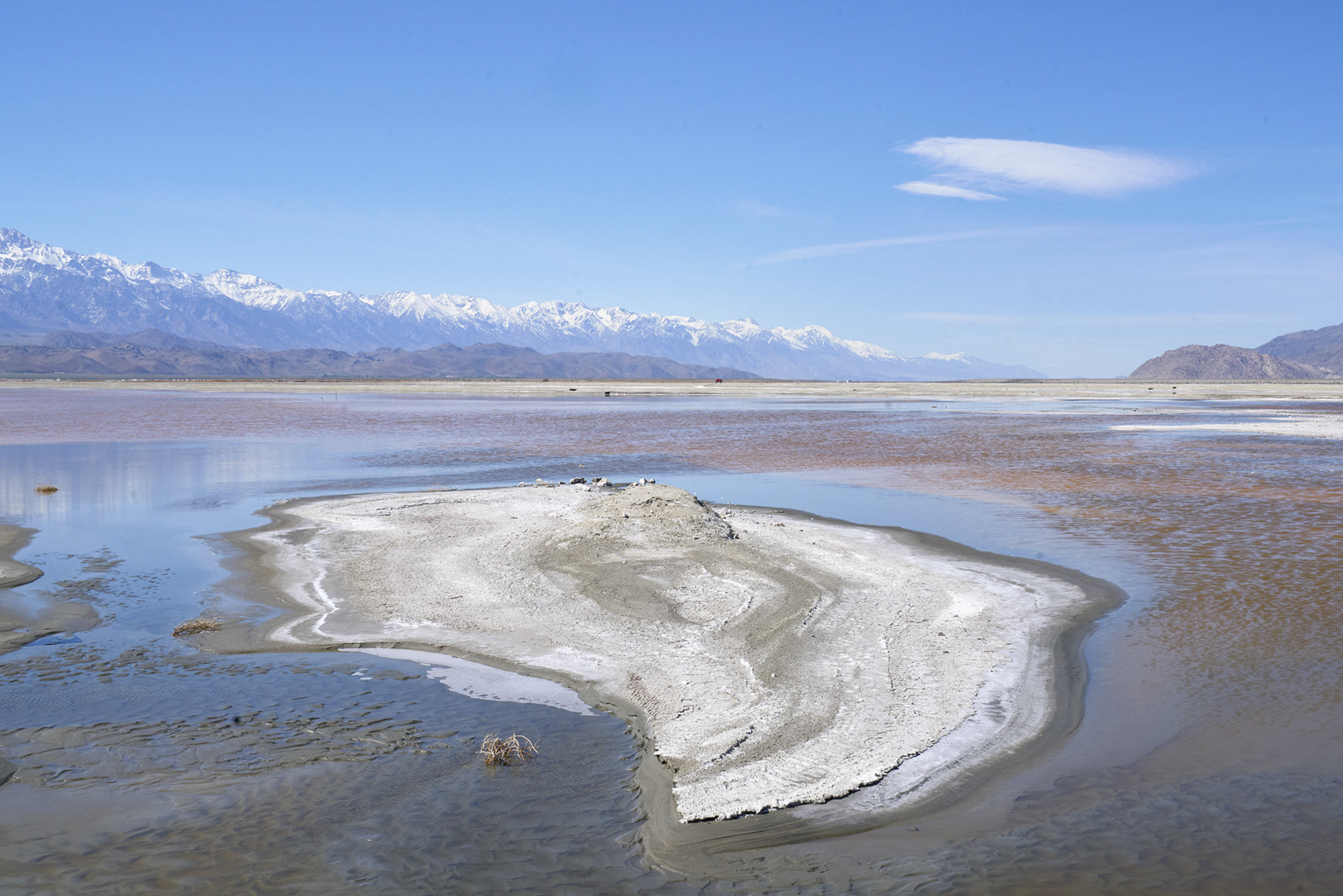 White dust covering a lakebed with blue sky in the background. 