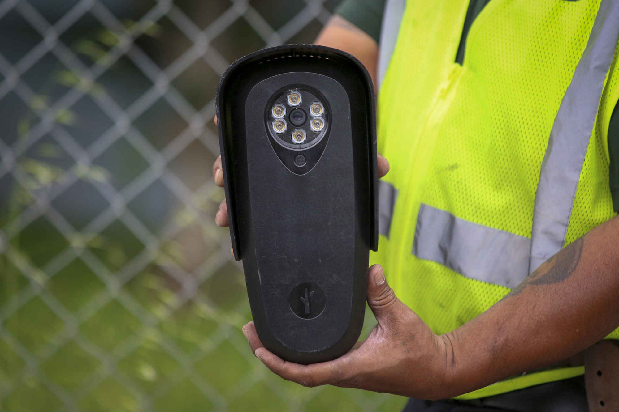 A man with a fluorescent yellow coat holds a black machine.