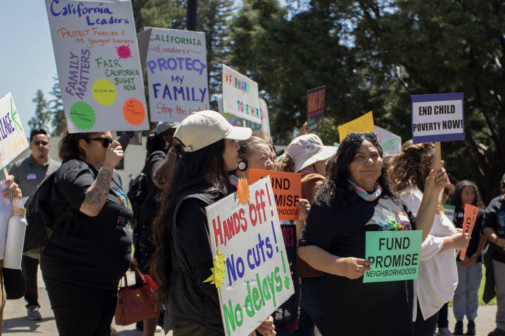 Women wearing dark clothing and holding signs stand together outside.