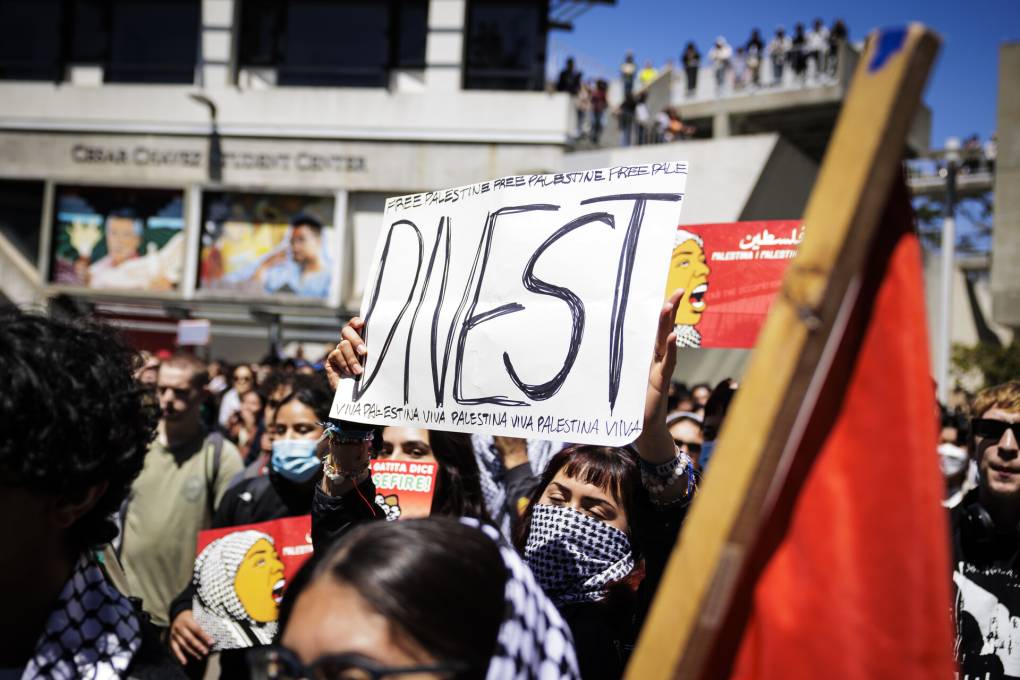 A group of young protesters holding a sign that says 'Divest.'