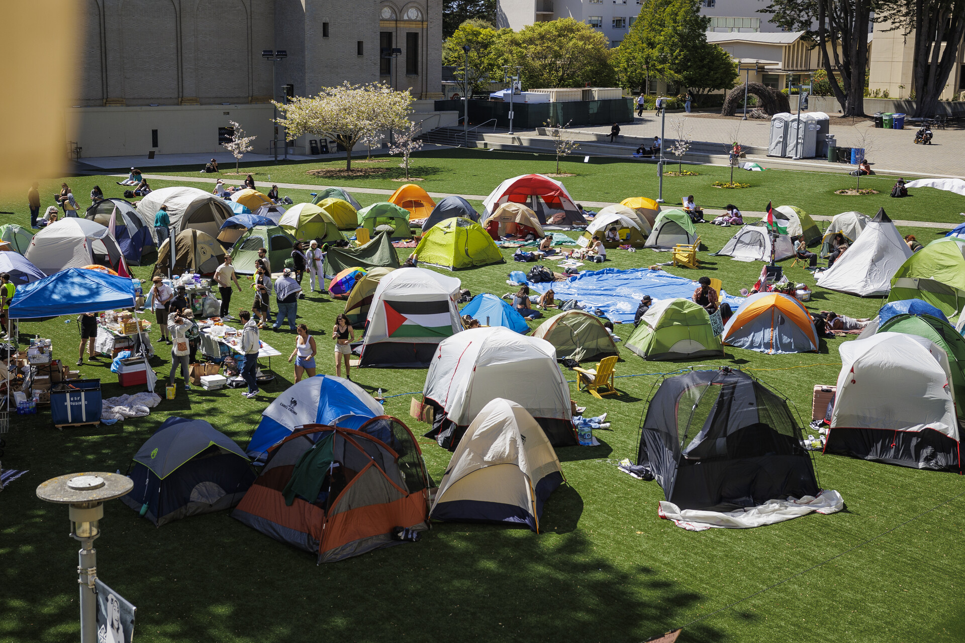 Tents are set up in a field surrounded by school buildings.