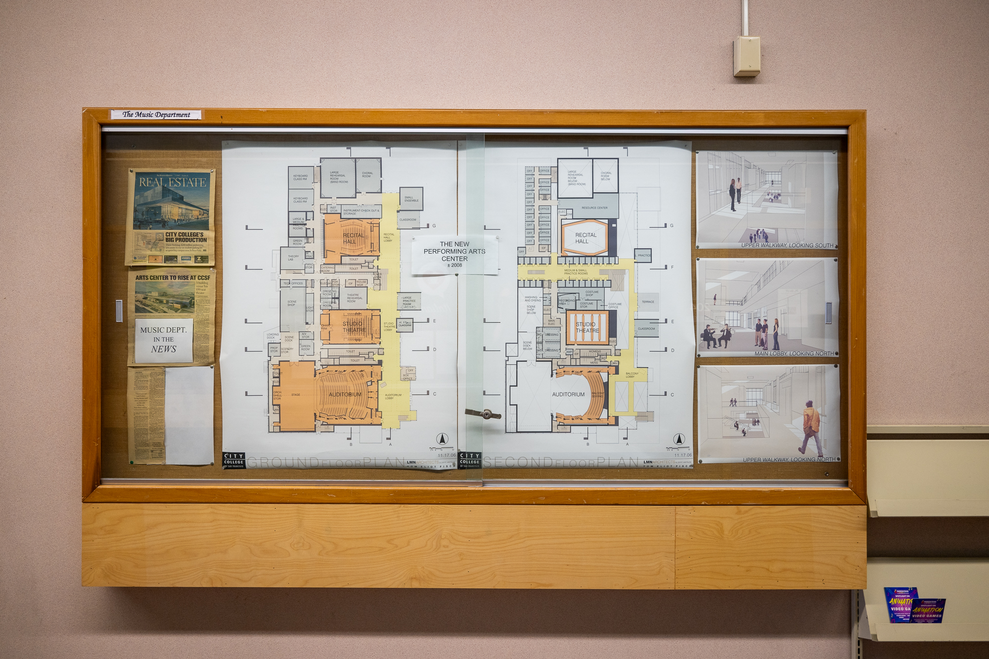 What appear to be detailed architectural renderings, including mock-up illustrations of an interior space, are displayed in a glass case
