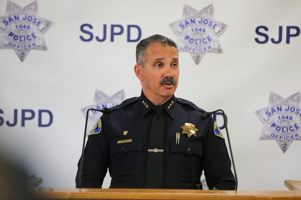 A police officer stands in front of a podium.