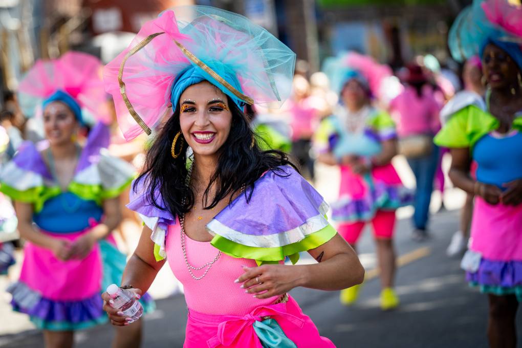 A woman dressed in a colorful costume walks during a parade.