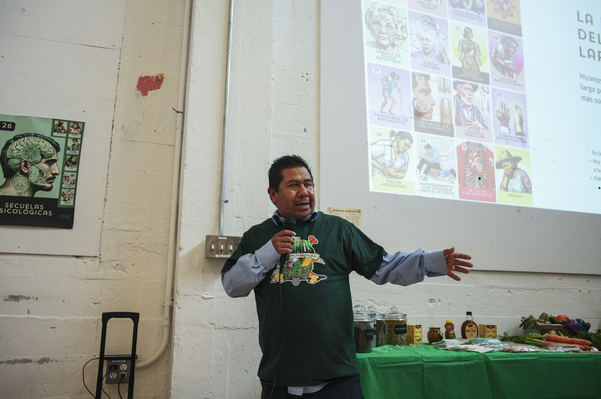 A middle-aged Latino man gestures during a presentation as he talks into a microphone.