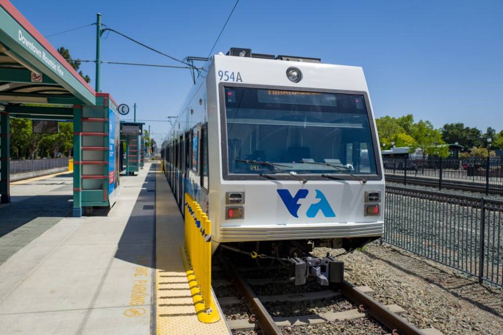 A train with "VTA" on the front pulls up to a station.