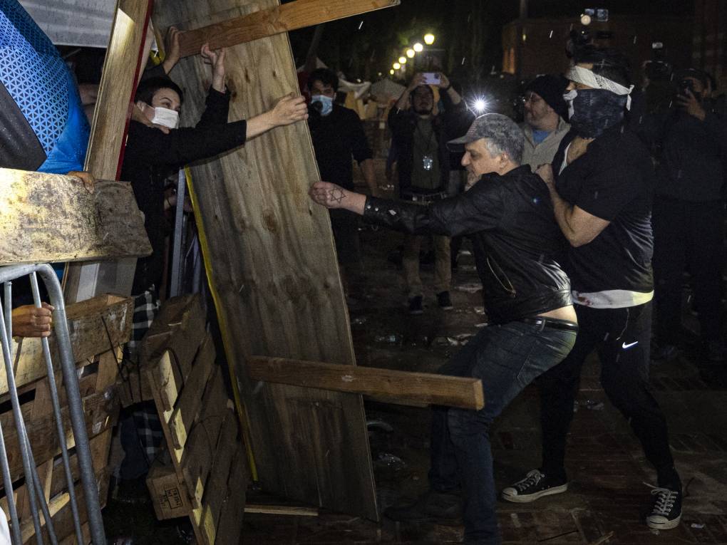 A protester dismantles a wooden structure.