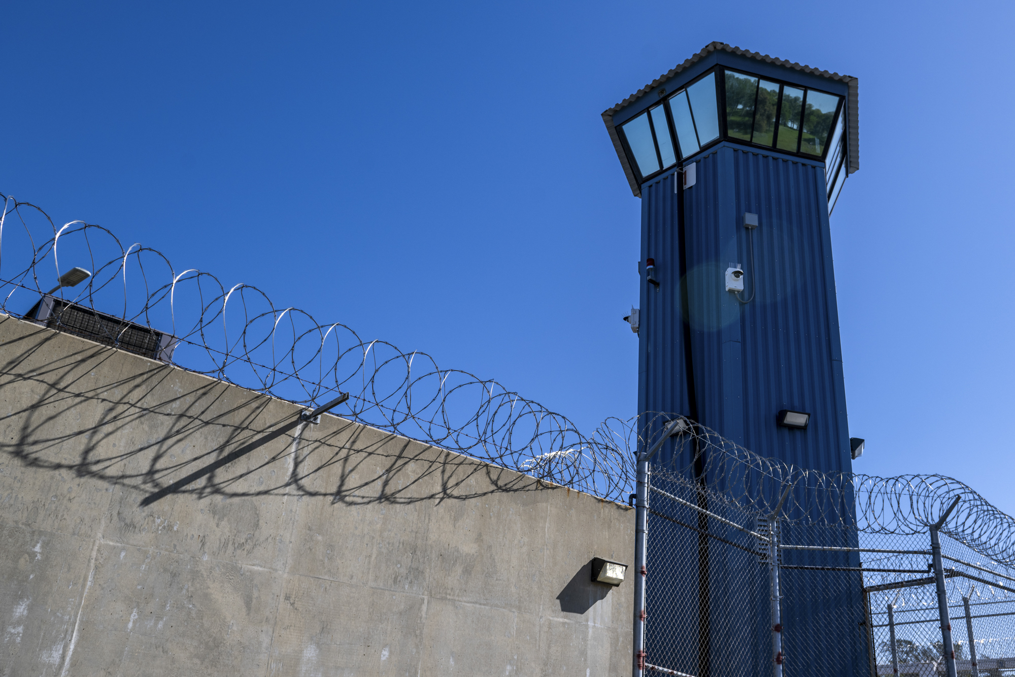A watchtower at a prison, with prison walls and barbed wire in the foreground.