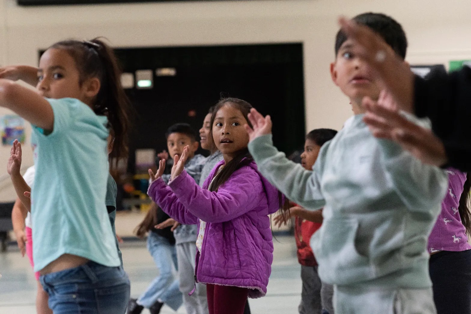 Students are standing with arms raised as part of a hip hop class activity.