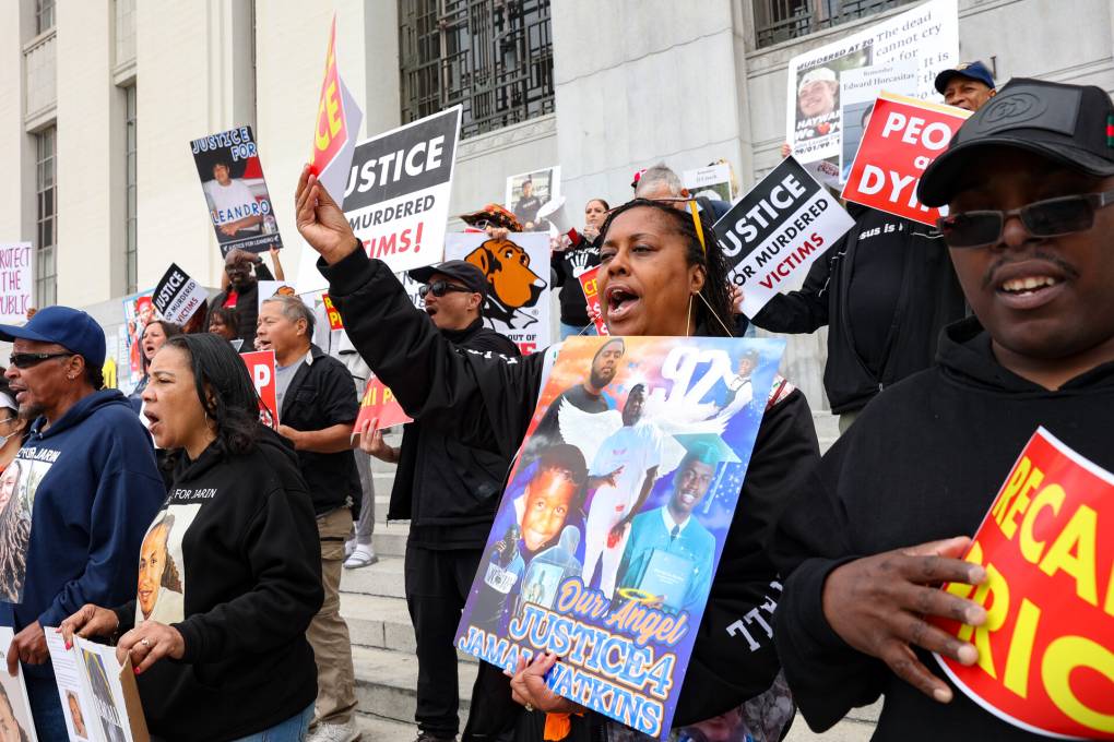 Demonstrators holding signs rally in front of a courthouse.