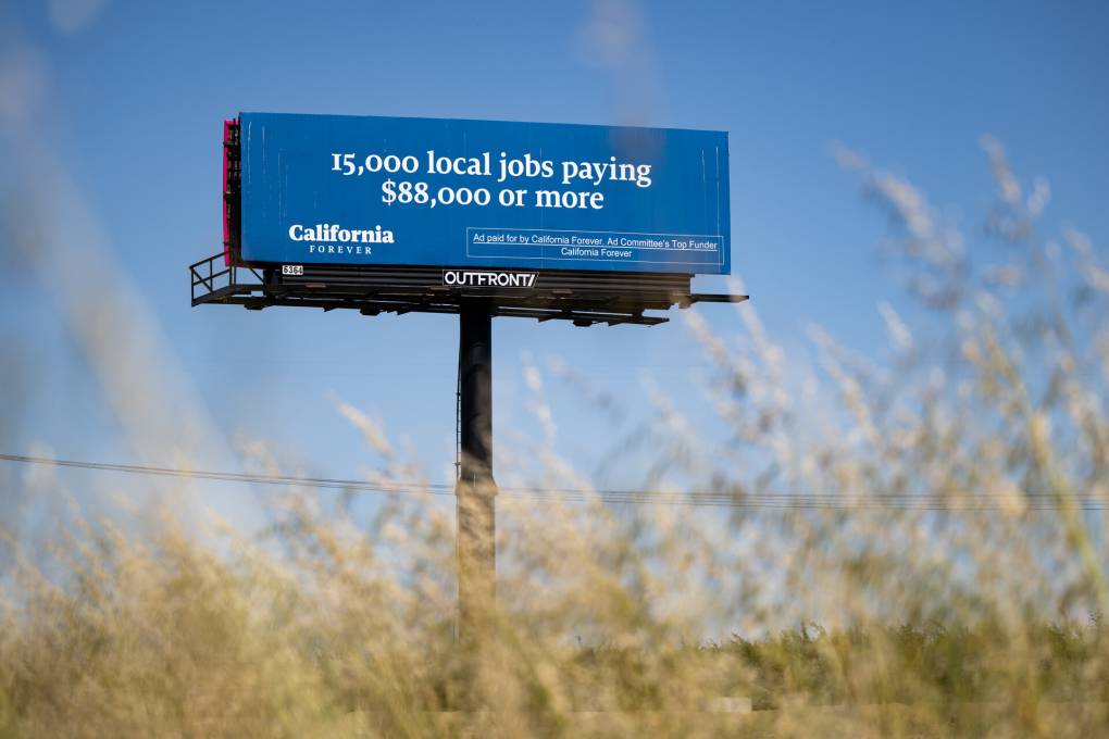 A billboard among tall weeds reads, "15,000 local jobs paying $88,000 or more." Paid for by California Forever.