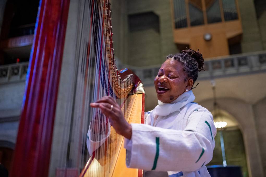 A woman dressed in white plays the harp.