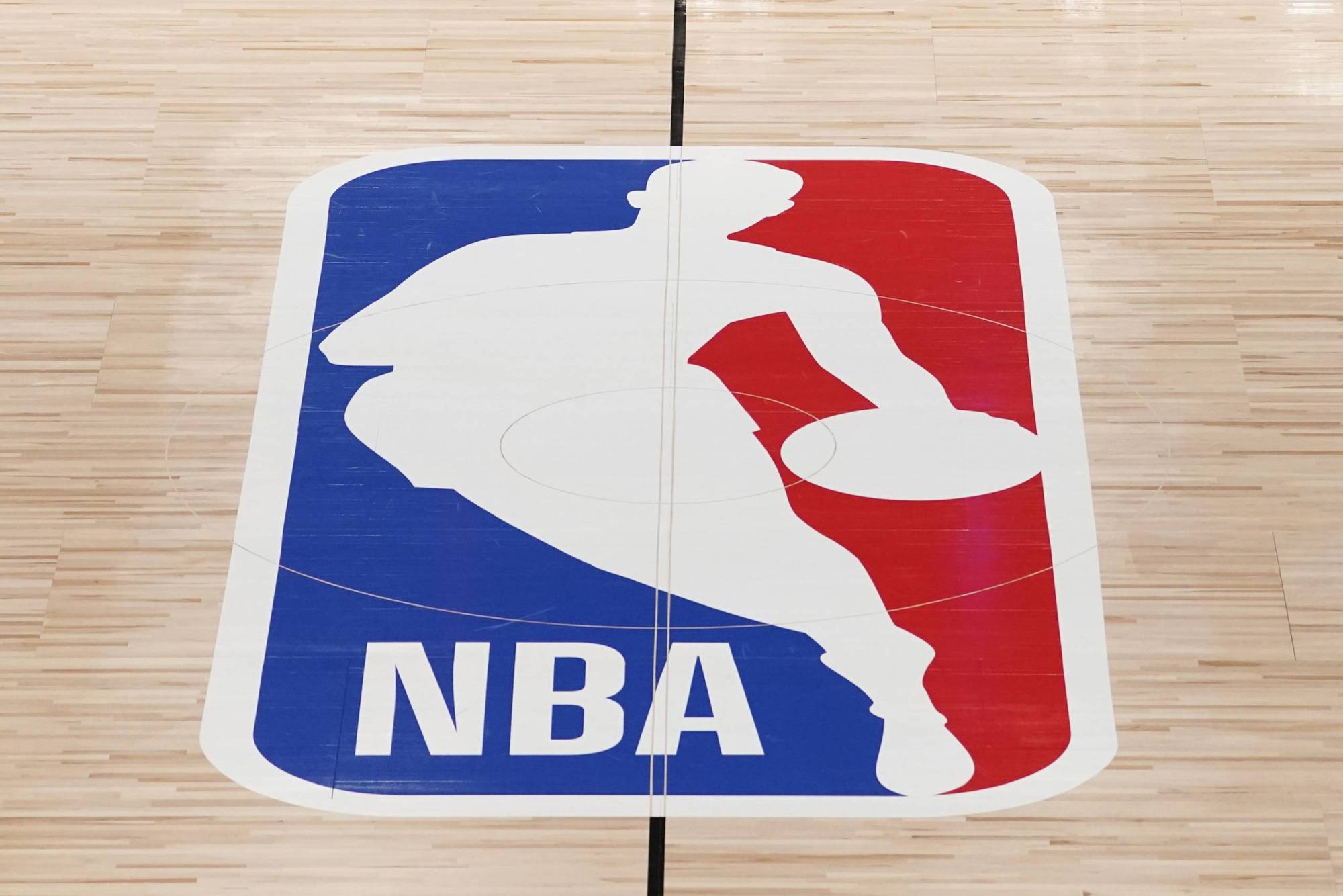 A logo of a blue, white and red silhouette with a man dribbling a basketball.