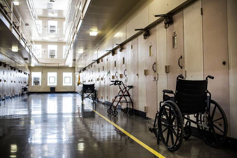 Wheelchairs and walkers sit outside prison cells.